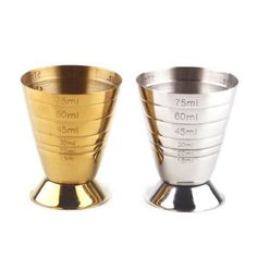 two measuring cups sitting side by side on top of each other, one is gold and the other is silver