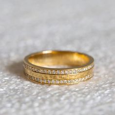 two gold wedding bands with small diamonds on them, sitting on a white carpeted surface