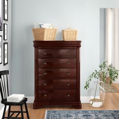 a dresser with baskets on top of it in a living room next to a chair