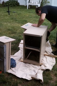 a man working on an unfinished cabinet in the yard