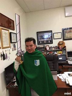 a man with a green cape on his head in an office