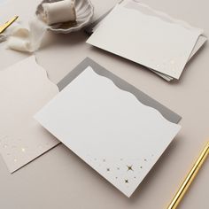 some white cards with gold stars on them next to a pen and paper roll,