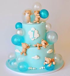 a blue cake with teddy bears on it and balloons in the shape of numbers 1