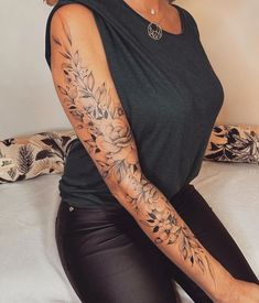 a woman sitting on top of a bed with tattoos on her arms and arm sleeves