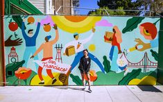 a woman standing in front of a mural on the side of a building