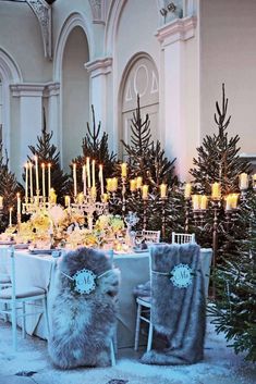 a dining room table set for christmas dinner with candles and trees in the background at night