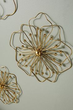 three metal wall hangings on the wall with gold balls and wire attached to them