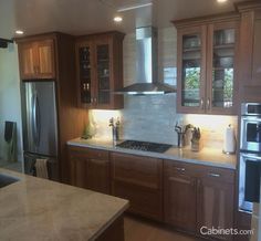 a kitchen with wooden cabinets and stainless steel appliances in the center, along with marble counter tops