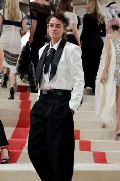 a young man in a tuxedo standing on the stairs at a fashion show