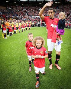 two children and an adult are standing in front of a soccer team on the field