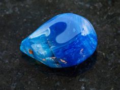 a blue glass object sitting on top of a black surface