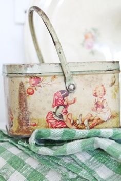 an old fashioned tin can is sitting on a green and white checkered tablecloth