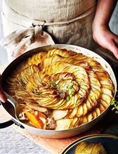 a pan filled with sliced potatoes on top of a wooden table