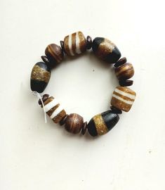 a beaded bracelet with brown, white and black beads on a white table top