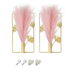 two gold and pink feathers are in front of a pair of earring hooks on a white background