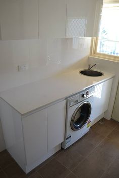 a washer and dryer are in the corner of a kitchen with tile flooring