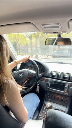 a woman sitting in the driver's seat of a car with her hand on the steering wheel