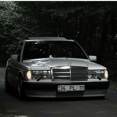 a mercedes benz parked in front of some trees