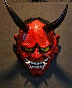 a red mask with horns and fangs on it's face is seen in this image