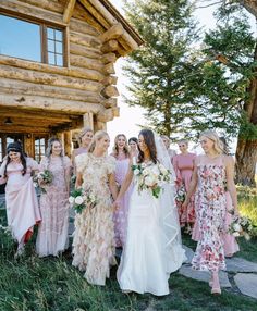 a group of women standing next to each other in front of a log cabin building