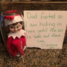 an elf is sitting next to a sign that says dad farted so i am hiding in there until the air is safe out there