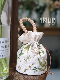 a small bag with flowers in it sitting on a table next to a glass bottle