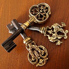 two antique keys on a wooden table with ornate handles and knobs in the shape of hearts