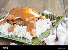 a green plate topped with rice and meat covered in gravy - stock image