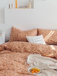 a bed with an orange and white flowered comforter on it's side