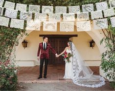 a bride and groom holding hands in front of an archway decorated with paper cutouts