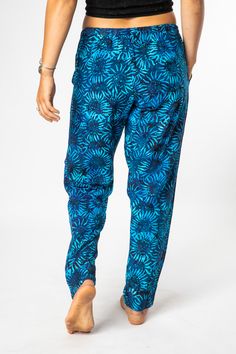 A combination of cool comfort and colorful hippie style are all yours when you slip into these breezy batik straight legged lounge pants. Featuring flowing rayon fabric and an elasticized waist with a drawstring for a cozy and comfortable fit. Each pair of drawstring comfy pants was hand dyed and ethically made by our makers in Bali. The traditional Indonesian batik dye process is an ancient artform and each pair of one of a kind pants helps support this ancient artistic tradition. The perfect p Bohemian Floral Print Pants For Loungewear, Blue Relaxed Fit Harem Pants For Beach, Blue Floral Print Bottoms For Festival, Bohemian Harem Pants For Loungewear, Bohemian Ankle-length Harem Pants For Loungewear, Hippie Harem Pants For Loungewear, Tie Dye Pants With Elastic Waistband For Loungewear, Blue Relaxed Fit Harem Pants For Vacation, Hippie Harem Pants With Elastic Waistband For Loungewear