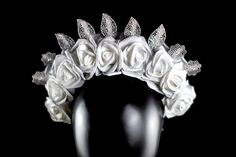 Introducing one of our reversible crowns--a work of art that embodies the delicate balance between modern innovation and timeless beauty. This exceptional crown showcases a stunning harmony of elements. It features gentle white zip ties, pristine white roses, radiant silver roses, and intricate metal silver leaves, making it a reversible masterpiece that offers two distinct yet equally captivating looks. One side of the crown is adorned with delicate white roses that exude a gentle elegance, sym White Pinched Crown For Wedding, White Wedding Crown With Pinched Shape, Luxury Wedding Headpieces, Silver Headband Crown For Wedding, White Crown Headpieces As Gift, Wedding Headpiece With Tall Crown Design, Silver Wedding Crown With Pinched Shape, Elegant Silver Crown For Wedding, White Crown Design Jewelry For Wedding