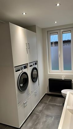 a washer and dryer in a very large room with two windows on the wall