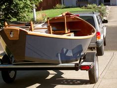 a small boat sitting on the back of a truck parked in front of a house