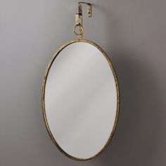 an oval mirror hanging on the wall next to a hook with a chain around it