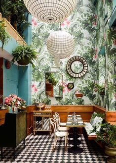 the interior of a restaurant decorated with tropical wallpaper and potted plants on the walls