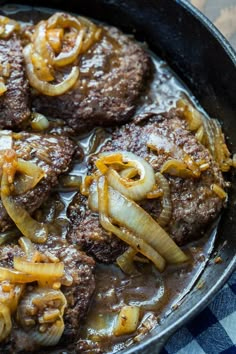 some meatballs and onions are cooking in a skillet on the stove top with a blue checkered table cloth