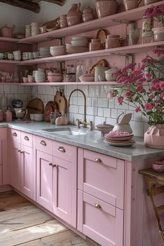 a kitchen with pink cabinets and shelves filled with pots, pans, and flowers