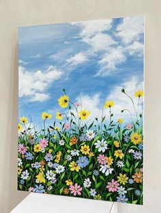 a painting of daisies and wildflowers against a blue sky with white clouds