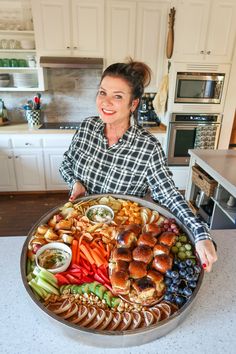 a woman holding a large platter of food