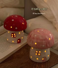 two mushroom shaped lights sitting on top of a table next to an open book and pillow