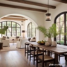 a dining room table with chairs and vases on it in front of arched windows