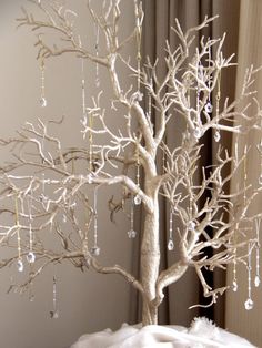 a white tree with beads hanging from it's branches in front of a window