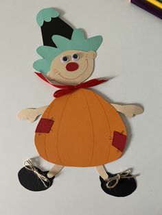 a paper cut out of a clown on top of a table with crayons