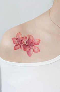 a woman's shoulder with a pink flower tattoo on the left side of her chest