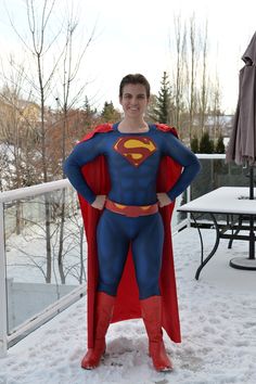 a man dressed as superman standing in the snow