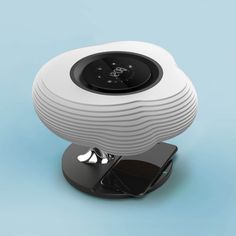 a white speaker sitting on top of a black stand next to a blue wall and floor