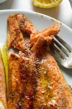 a white plate topped with fish next to a fork