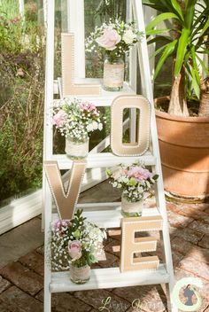 an old ladder is decorated with flowers and the word love spelled out in cursive letters