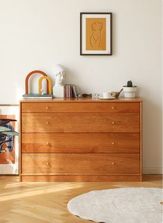 a wooden dresser sitting next to a white rug on top of a hard wood floor